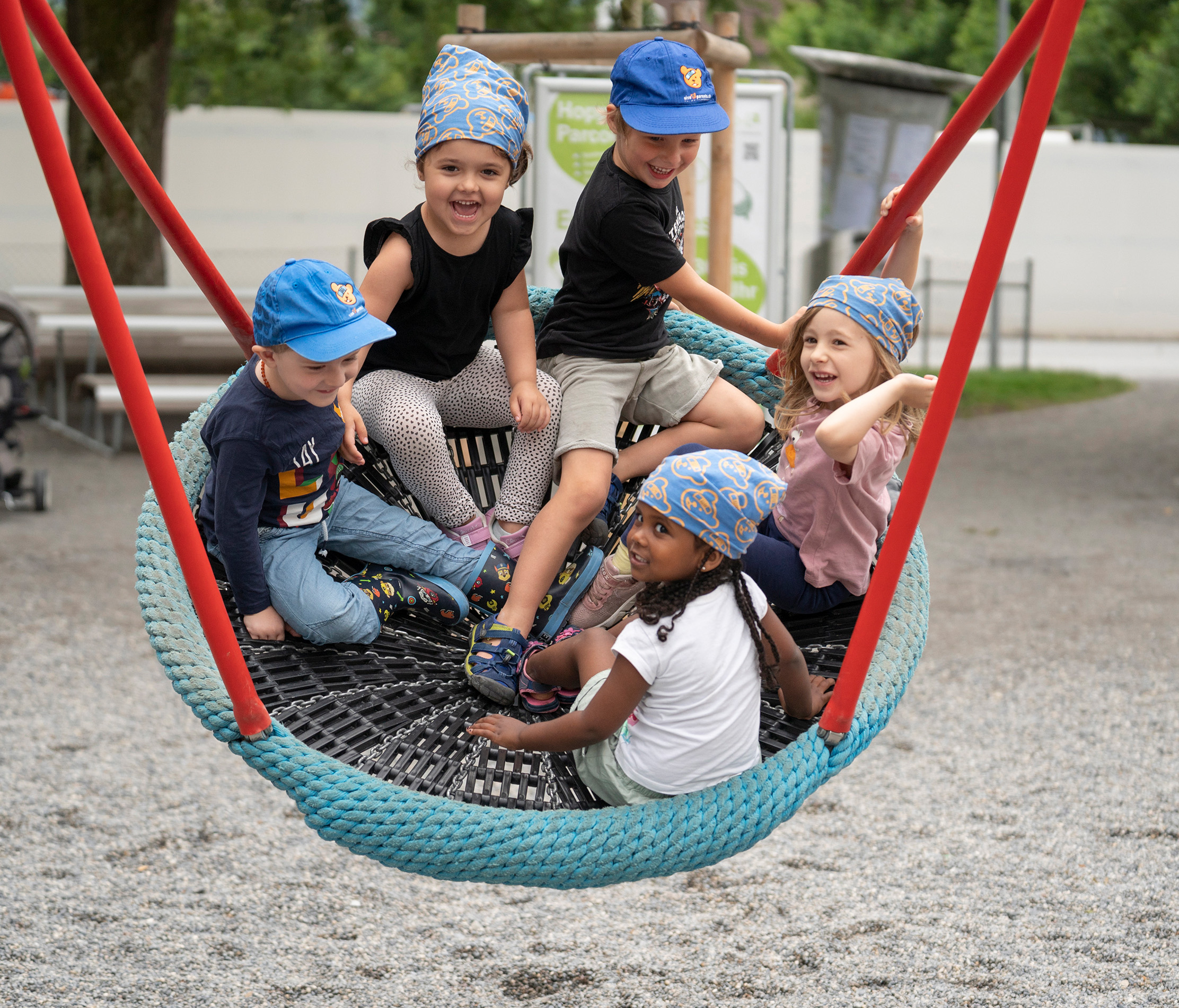 Kita-Kinder schaukeln im Korb auf dem Spielplatz