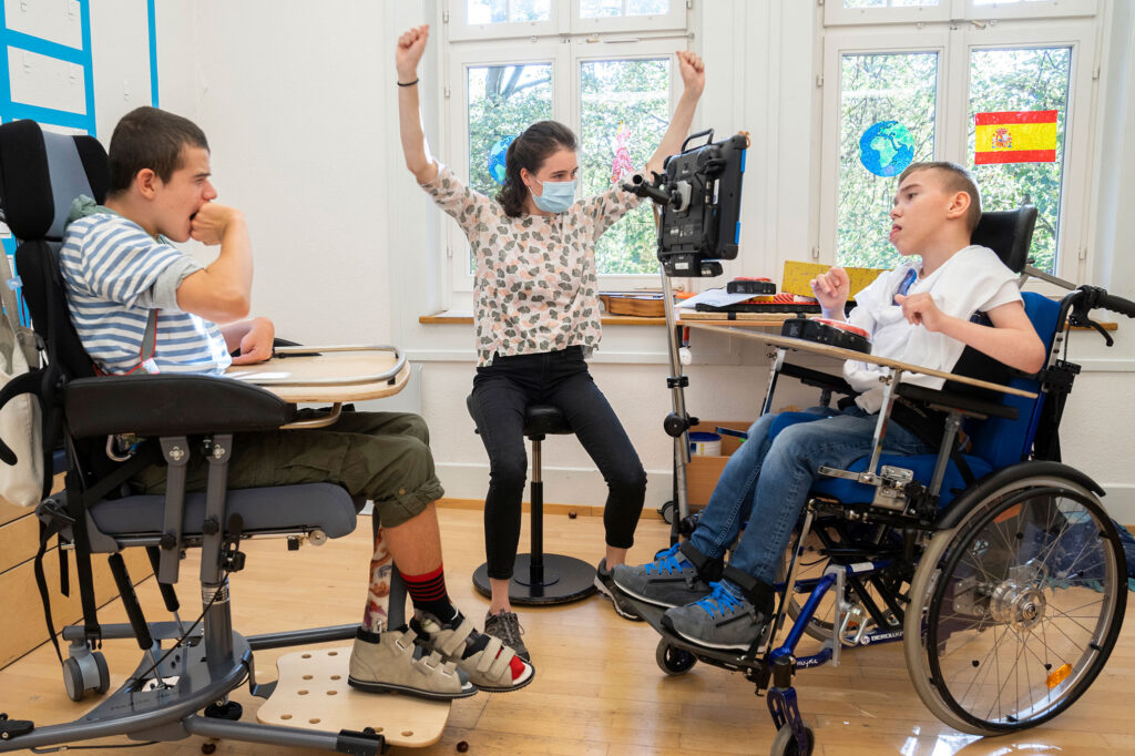 Betreuerin bei der Stiftung visoparents macht Übungen mit zwei Kindern im Rollstuhl.