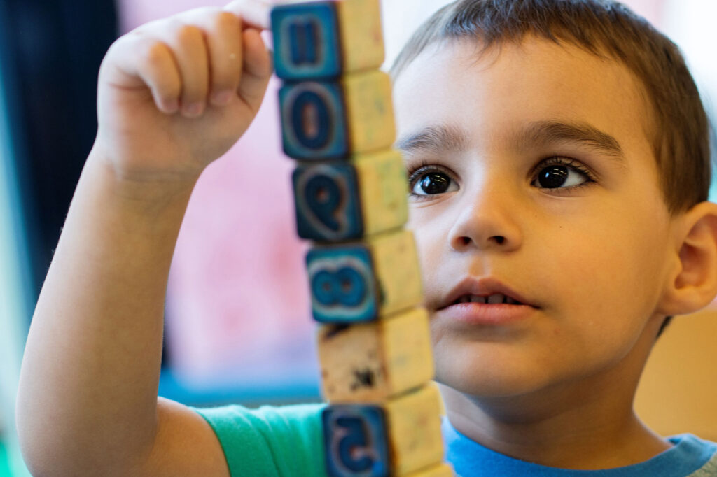 Ein Junge baut einen Turm aus Holzwürfeln in der integrativen Kita Kinderhaus Imago 